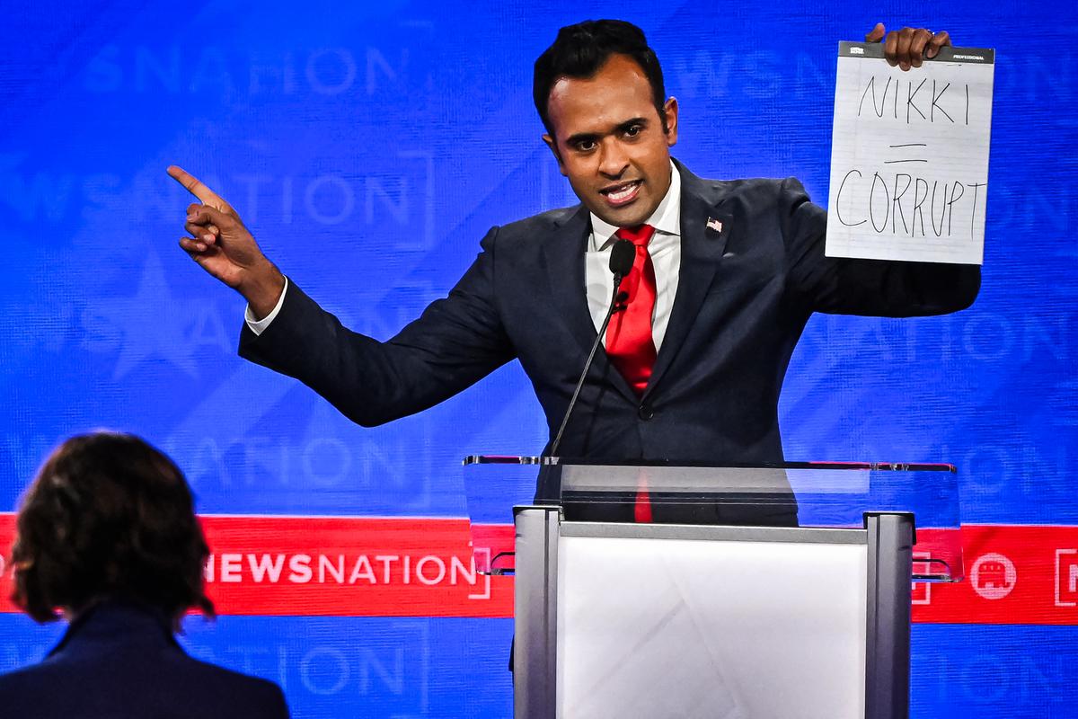 Candidate Vivek Ramaswamy holds up a sign reading "Nikki = corrupt," referring to former U.N. ambassador Nikki Haley during the fourth Republican presidential primary debate at the University of Alabama in Tuscaloosa, Ala., on Dec. 6, 2023. (Jim Watson/AFP via Getty Images)