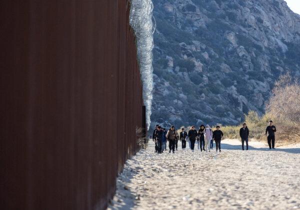 Illegal immigrants who passed through a gap in the U.S. border wall await processing by Border Patrol agents in Jacumba, Calif., on Dec. 7, 2023. (John Fredricks/The Epoch Times)