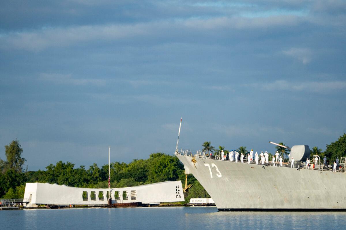 Sailors aboard the the USS Decatur render honors while passing the USS Arizona Memorial and the sunken battleship the USS Arizona during the 82nd Pearl Harbor Remembrance Day ceremony at Pearl Harbor in Honolulu, Hawaii, on Dec. 7, 2023. (Mengshin Lin/AP Photo)