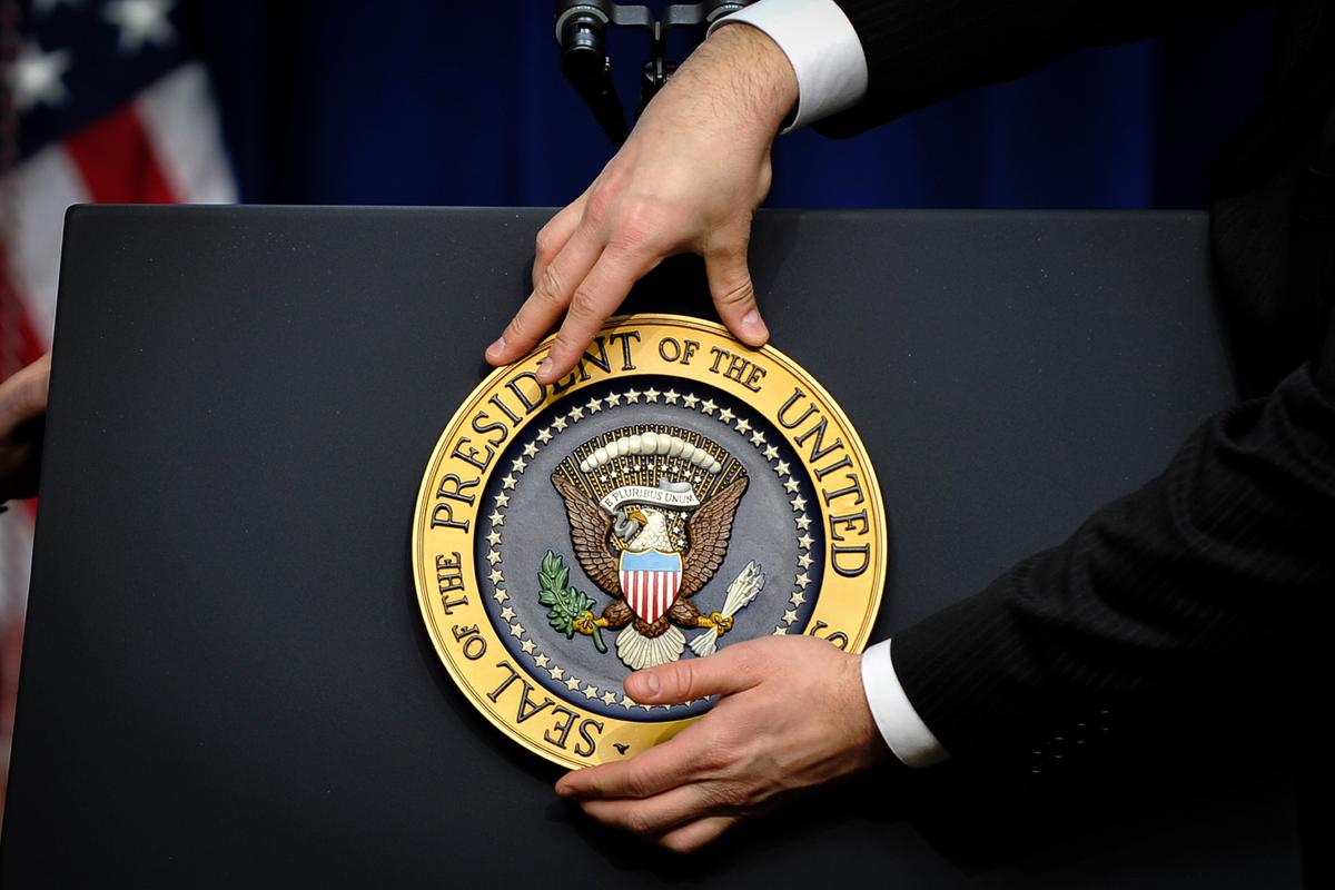 A staff member fixes the presidential seal before President Barack Obama gives a press conference at the White House on Dec. 22, 2010. (Jewel Samad/AFP via Getty Images)