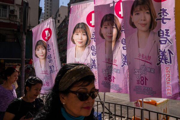 Pedestrians walk past posters promoting candidates during the District Council elections in Hong Kong on Dec. 10, 2023. (Louise Delmotte/AP Photo)