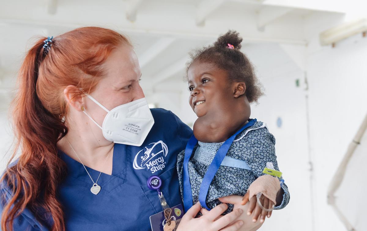 Umu is held by one of the staff at Mercy Ships prior to surgery. (SWNS)