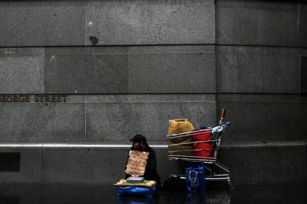 A homeless man waits for charity in the rain in central Sydney, Australia, on May 29, 2020. (Saeed Khan/AFP via Getty Images)