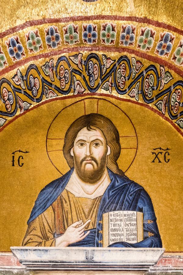 As visitors enter the Katholikon, they pass a large, gilded mosaic of Christ, referred to as “Pantocrator” by the Byzantines, meaning “all-powerful ruler” or “ruler of all.” The mosaic is in gold tesserae and depicts Christ draped in a blue cloth and holding an open book, proclaiming him to be the “light of the world” (John 8:12). Gold tesserae was often used in Middle Byzantine churches and consists of applying very fine gold leaf between two pieces of clear or lightly tinted glass. (Joaquin Ossorio Castillo/Shutterstock)