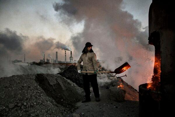 A Chinese laborer loads coal into a furnace as smoke and steam rises from an unauthorized steel factory in Inner Mongolia, China, on Nov. 3, 2016. (Kevin Frayer/Getty Images)