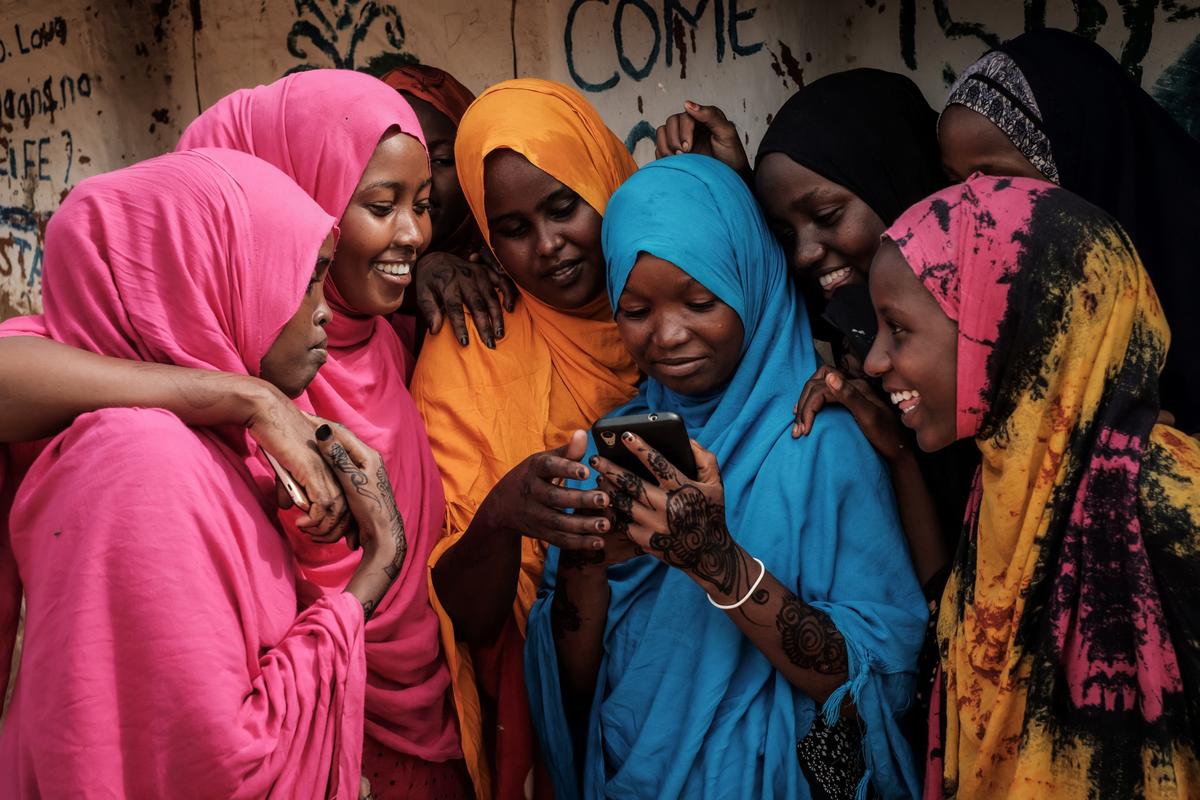 Young Somali women look at a smartphone at Dadaab refugee complex, in the northeast of Kenya, on April 16, 2018. (Yasuyoshi Chiba/AFP via Getty Images)