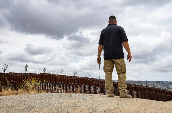 Manny Bayon, a U.S. Border Patrol agent, listens to radio chatter near the U.S. border wall in San Diego on May 31, 2023. (John Fredricks/The Epoch Times)