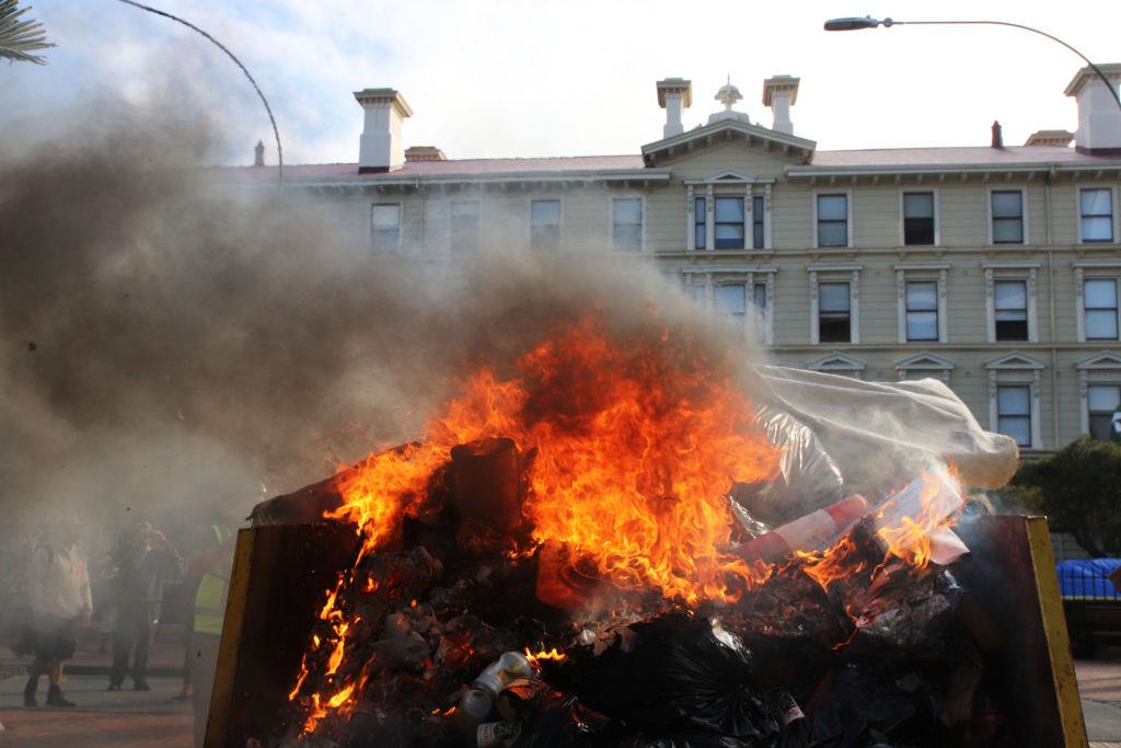 A fire burns in a rubbish skip on Bunny Street near Parliament and Victoria University after riot police moved to break up the occupation of Parliament's grounds in Wellington, New Zealand on March 2, 2022. (Lynn Grieveson/Getty Images)
