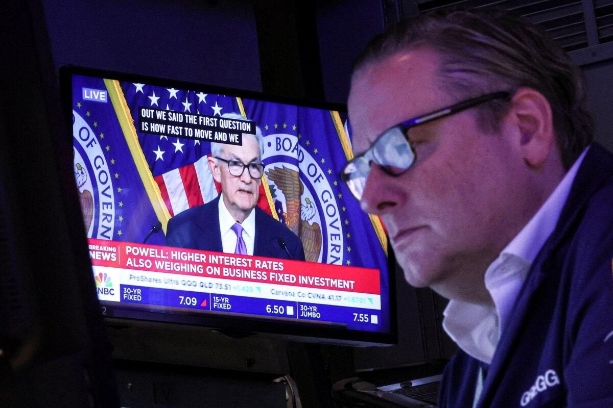 A trader works as a screen displays a news conference by Federal Reserve Board Chairman Jerome Powell following the Fed rate announcement on the floor of the New York Stock Exchange on Dec. 13, 2023. (Brendan McDermid/Reuters)