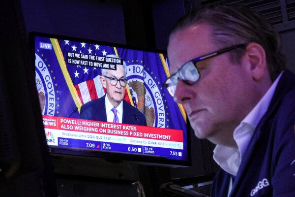 A trader works, as a screen displays a press conference by Federal Reserve Board Chairman Jerome Powell following the Fed rate announcement, on the floor of the New York Stock Exchange on Dec. 13, 2023. (Brendan McDermid/Reuters)