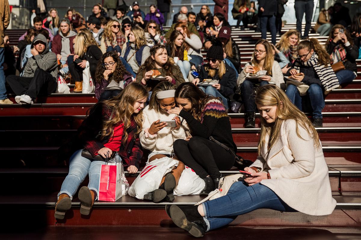 A group of teens look at a photograph taken on a smartphone in Times Square in New York City on Dec. 1, 2017. (Drew Angerer/Getty Images)