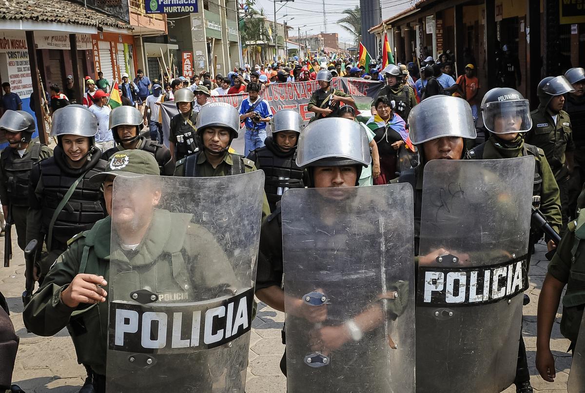 Riot police escort a group of sympathizers to Bolivian President Evo Morales's party, Movement to Socialism, as they enter the city of Montero, north of Santa Cruz, Bolivia, on Sept. 24, 2008. (Aizer Raldes/AFP via Getty Images)