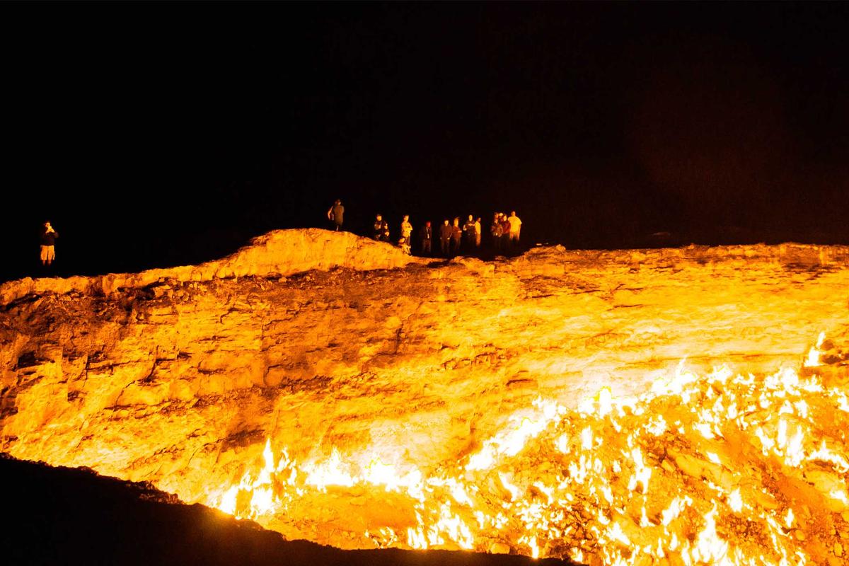 Visitors contemplate the flames at night at the Darvaza Crater in Turkmenistan. (Antonin Vinter/Shutterstock)