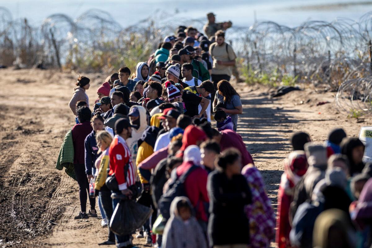 A group of more than 1,000 illegal immigrants wait in line near a U.S. Border Patrol field processing center after crossing the Rio Grande from Mexico, in Eagle Pass, Texas, on Dec. 18, 2023. (John Moore/Getty Images)