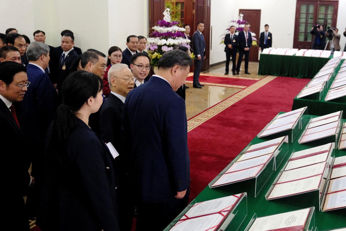 Chinese leader Xi Jinping (C) and Vietnamese Communist Party General Secretary Nguyen Phu Trong (center L) walk past signed agreements displayed at the Central Office of the Communist Party of Vietnam in Hanoi, Vietnam, on Dec. 12, 2023. (Minh Hoang/Pool/AFP via Getty Images)
