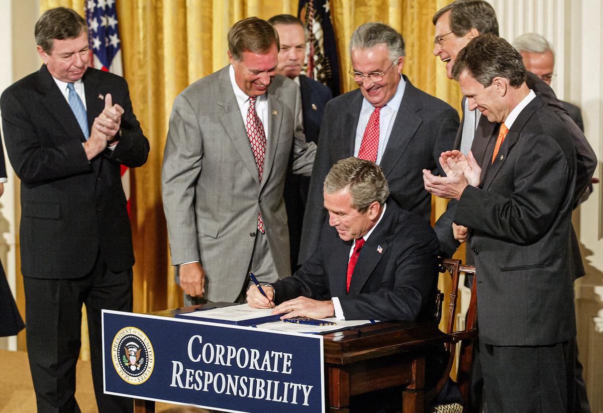  President George W. Bush signs the Sarbanes-Oxley Act as (L–R) Attorney General John Ashcroft, Rep. Michael Oxley (R-Ohio), Secretary of Commerce Donald Evans, Sen. Paul Sarbanes (D-Md.), Senate Minority Leader Trent Lott (R-Miss.) and Senate Majority Leader Tom Daschle (D-S.D.) look on, in the East Room of the White House on July 30, 2002. (Alex Wong/Getty Images)