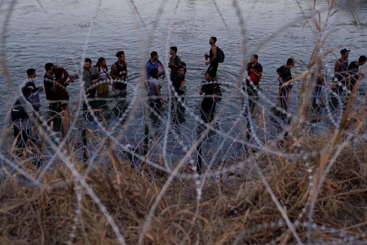 Illegal immigrants wait to climb over concertina wire after they crossed the Rio Grande and entered the United States from Mexico, in Eagle Pass, Texas, on Sept. 23, 2023. (Eric Gay/AP Photo)