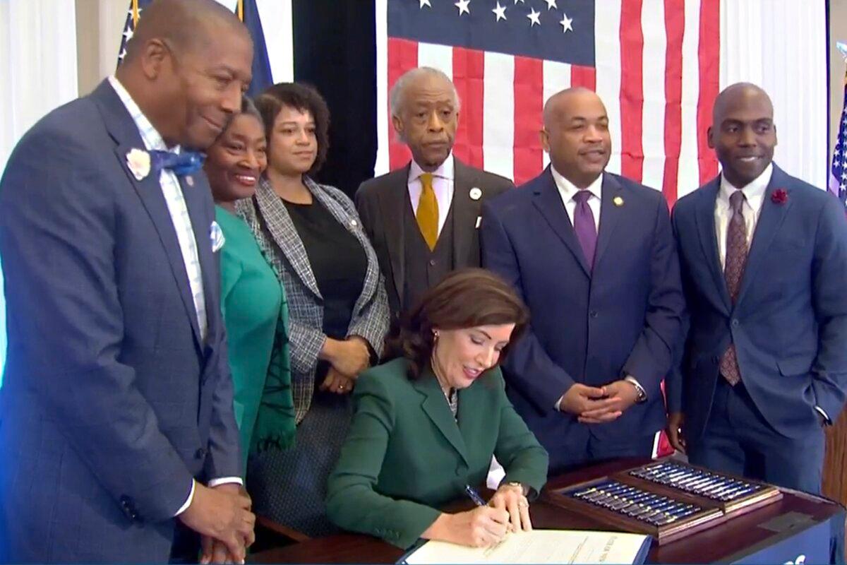 New York Gov. Kathy Hochul signs a bill in Albany, N.Y., on Dec. 19, 2023, to create a commission tasked with considering reparations to address the effects of slavery in the state. (Office of the Governor via AP)