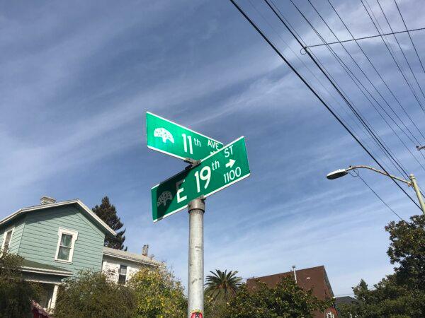 A street sign where the shrine is located on the corner of 11th Ave. and E 19th St. in Oakland, Calif., on Dec. 5, 2023. (Helen Billings/The Epoch Times)