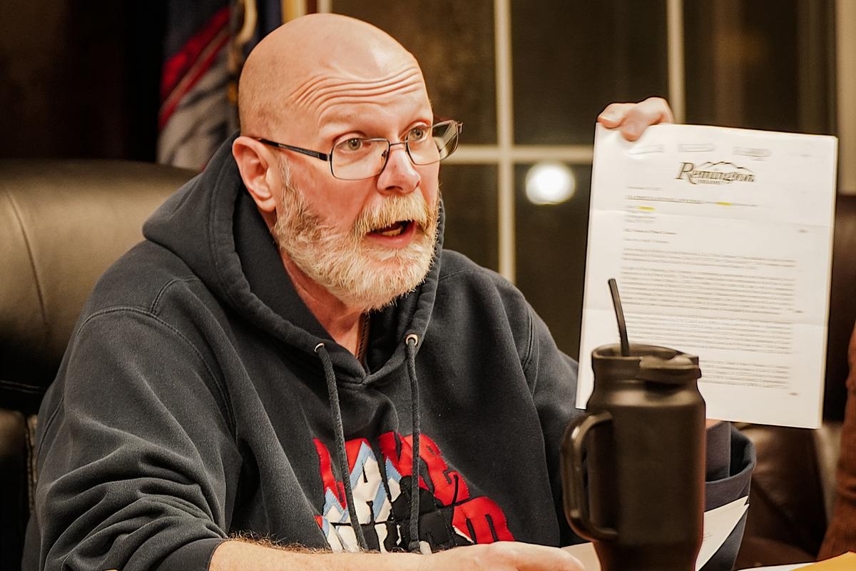 John Stephens, mayor of the village of Ilion, holds up a document from Remington Arms Co. during a Village Board of Trustees meeting in Ilion, N.Y., on Dec. 11, 2023. (Allan Stein/The Epoch Times)