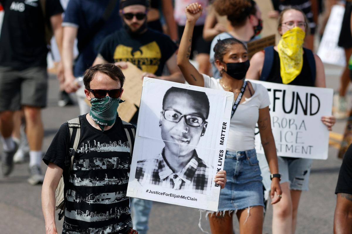 A demonstrator carries an image of Elijah McClain during a rally and march in Aurora, Colo., on June 27, 2020. (David Zalubowski/AP Photo)