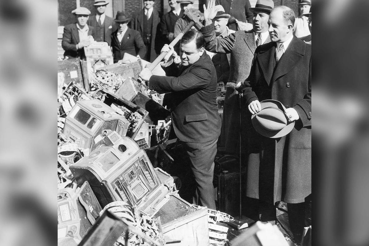Former New York City Mayor Fiorello La Guardia raises a sledgehammer over his shoulder prior to smashing slot machines piled up on a street after gambling raids in New York City, around 1935. (Hulton Archive/Getty Images)