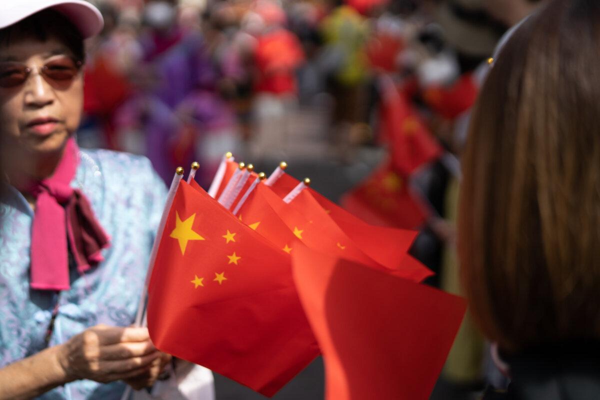 A woman hands out Chinese national flags during a parade celebrating China's National Day at Yokohama China Town in Yokohama, Japan, on Oct. 1, 2023. (Tomohiro Ohsumi/Getty Images)