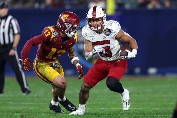 Isaac Guerendo (23) of the Louisville Cardinals rushes the ball past the defense of Mason Cobb (13) of the USC Trojans during the first half of the Holiday Bowl at Petco Park on December 27, 202in San Diego on Dec. 27, 2023. (Sean M. Haffey/Getty Images)