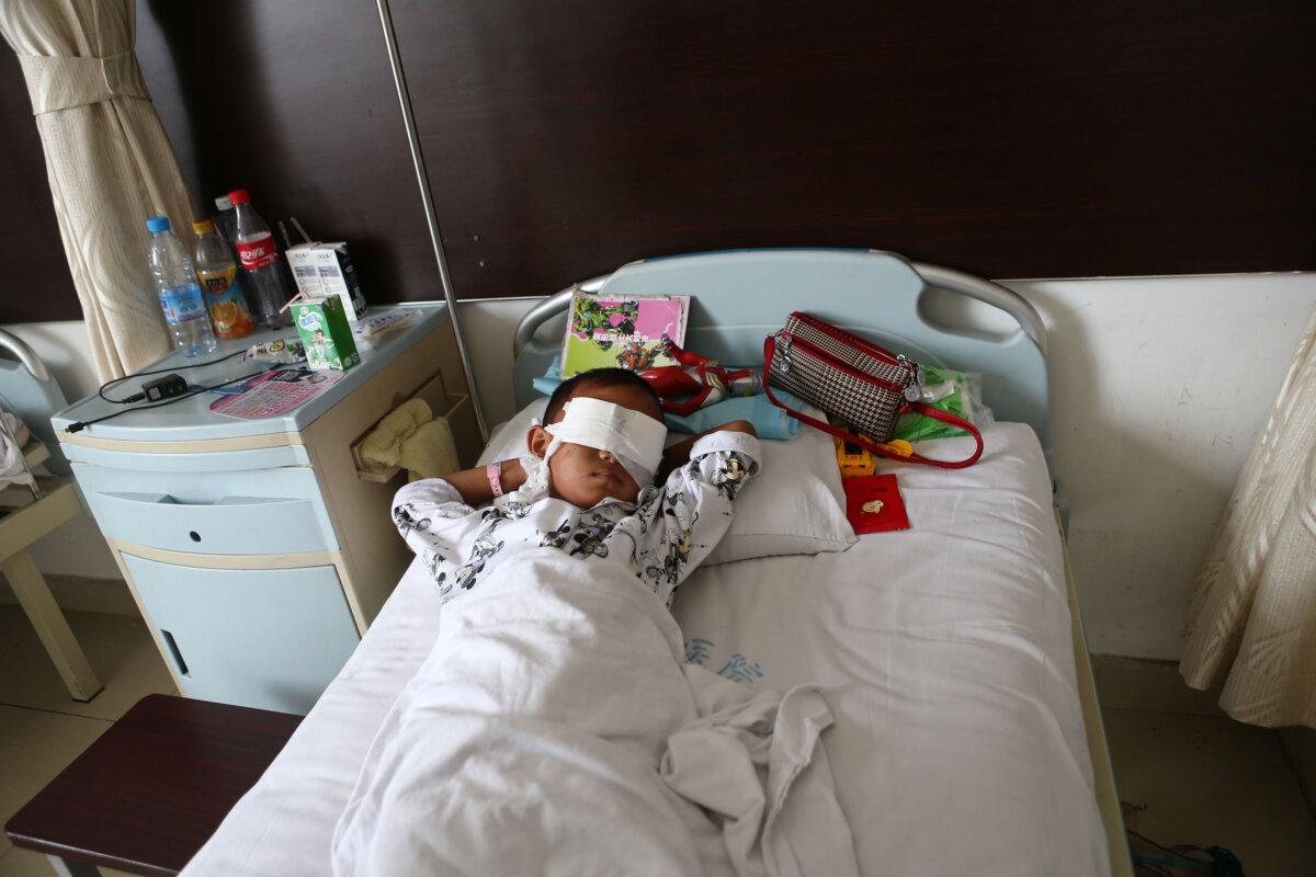 A boy lies on his hospital bed with his eyes covered with bandages in a hospital in Taiyuan, north China's Shanxi province on August 27. (STR/AFP via Getty Images)
