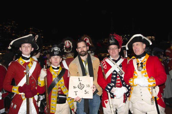 Dustin Bass (C), holding the logo of the East India Tea Company, stands with several British soldier reenactors. (Alan Wakim/Sons of History)