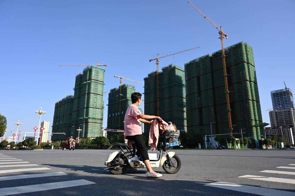 A woman rides a scooter past the construction site of an Evergrande housing complex in Zhumadian, central China's Henan Province on Sept. 14, 2021. (Jade Gao/AFP via Getty Images)