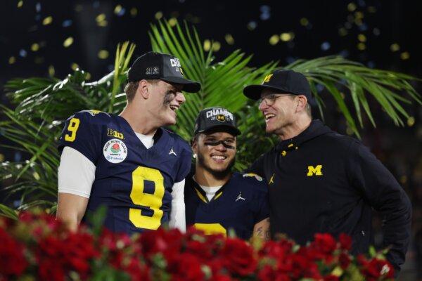 J.J. McCarthy (9), Blake Corum (2), and head coach Jim Harbaugh of the Michigan Wolverines celebrate after beating the Alabama Crimson Tide in overtime to win the CFP Semifinal Rose Bowl Game in Pasadena, Calif., on Jan. 1, 2024. (Harry How/Getty Images)