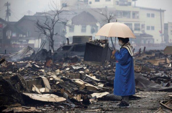 A woman looks at the burnt-out marketplace by a fire following earthquake in Wajima, Ishikawa prefecture, Japan, on Jan. 3, 2024. (Kyodo News via AP)