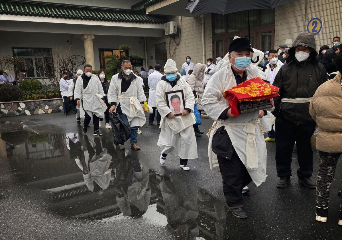 During his funeral in Shanghai, China on January 14, 2023, he and others carry the cremated remains of a loved one, just as he and others wear traditional white funeral clothes (Kevin Frayer) /Getty Images)