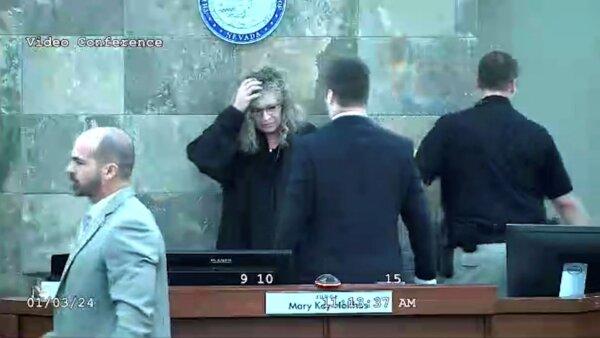In this image from video, Judge Mary Kay Holthus is seen cradling her head after a defendant launched over her desk during his sentencing in a felony battery case, in Las Vegas on Jan. 3, 2024. (Clark County District Court via AP)
