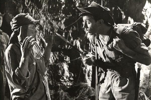 Pvt. Bamforth (Laurence Harvey, R) threatens captive Japanese soldier “Tojo” (Kenji Takaki), in “Jungle Fighters.” (Productions ABPC)