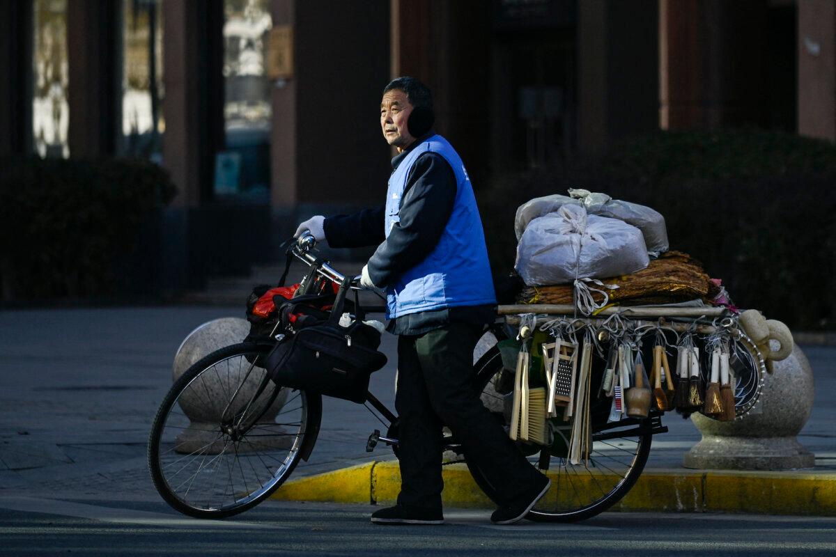 A vendor, pushing his bicycle, prepares to cross a street in Beijing on Jan. 3, 2024. (Wang Zhao/AFP via Getty Images)