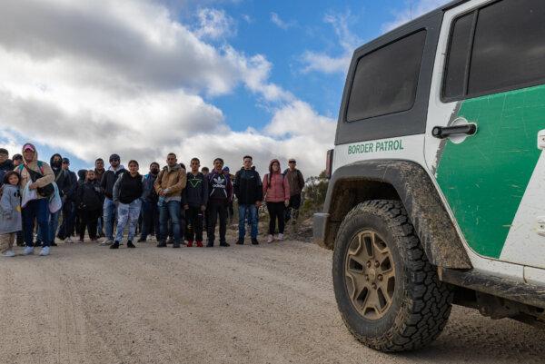 Illegal immigrants gather after crossing the United States border wall in Jacumba, Calif., on Jan. 10, 2024. (John Fredricks/The Epoch Times)
