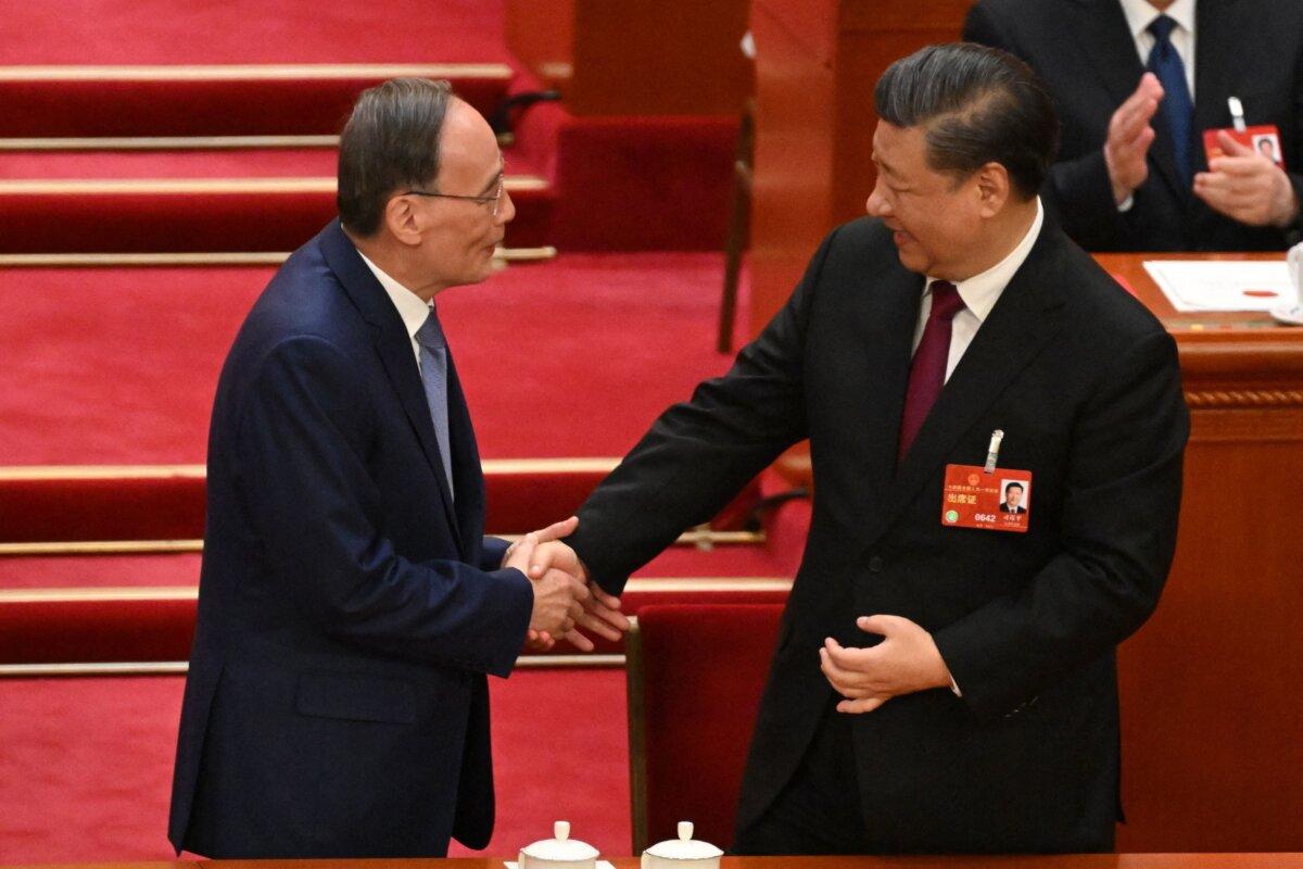 China's President Xi Jinping (R) shakes hands with former Vice President Wang Qishan (L) during the third plenary session of the National People's Congress (NPC) in Beijing on March 10, 2023. ( Noel Celis/AFP via Getty Images)