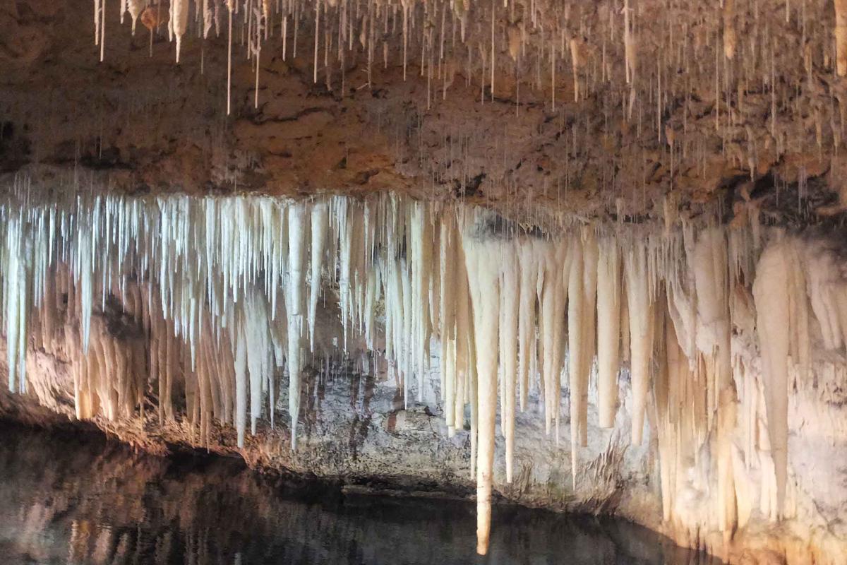Crystal formations hang over a subterranean lake. (GeographicVisions/Shutterstock)