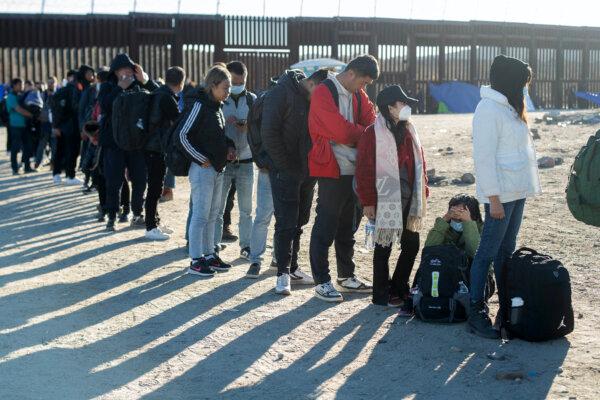 Immigrants who entered the United States illegally the day before through the border wall wait to be taken to a port of entry by border patrol agents in Jacumba, Calif., on Dec. 6, 2023. (Valerie Macon/AFP via Getty Images)