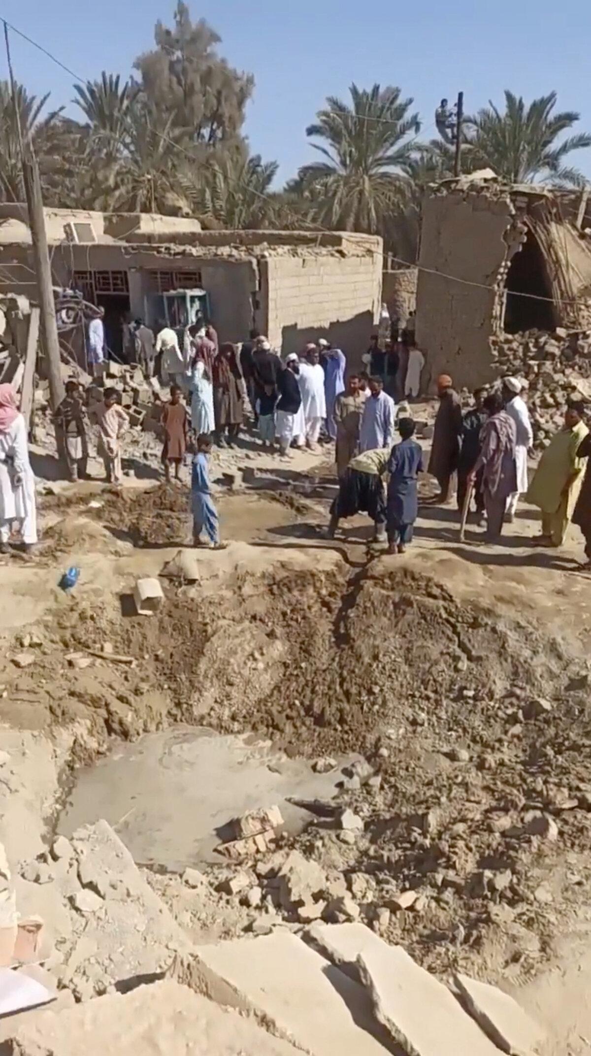 People gather near rubble in the aftermath of Pakistan's military strike on an Iranian village near Saravan, Sistan and Baluchestan Province, Iran, in this screen grab from social media video obtained by Reuters on Jan. 18, 2024.