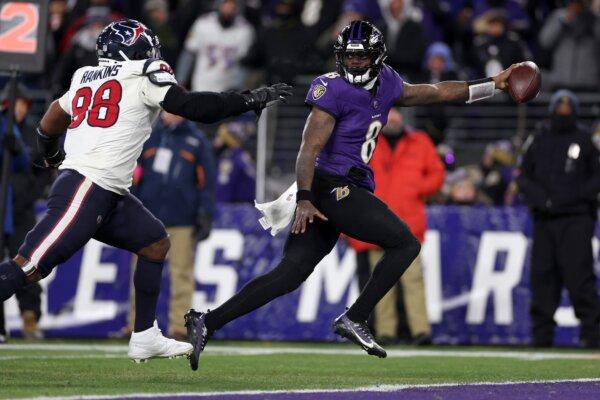 Lamar Jackson (8) of the Baltimore Ravens scores an 8-yard touchdown against Sheldon Rankins (98) of the Houston Texans during the fourth quarter in the AFC Divisional Playoff game in Baltimore on Jan. 20, 2024. (Patrick Smith/Getty Images)