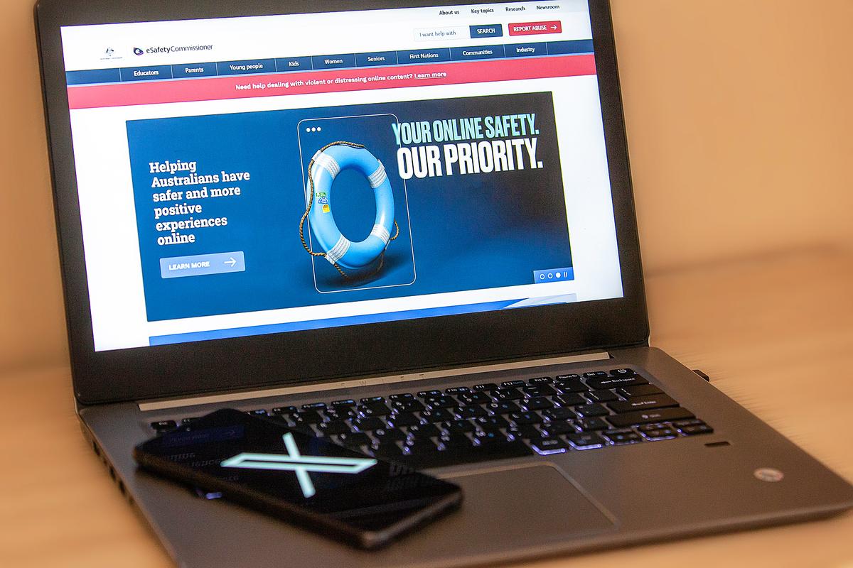 An image of the X (formerly Twitter) phone app in front of a laptop featuring the front page to Australia's eSafety commissioner website, taken in Perth, Western Australia on Jan. 22, 2024. (Wade Zhong/The Epoch Times)