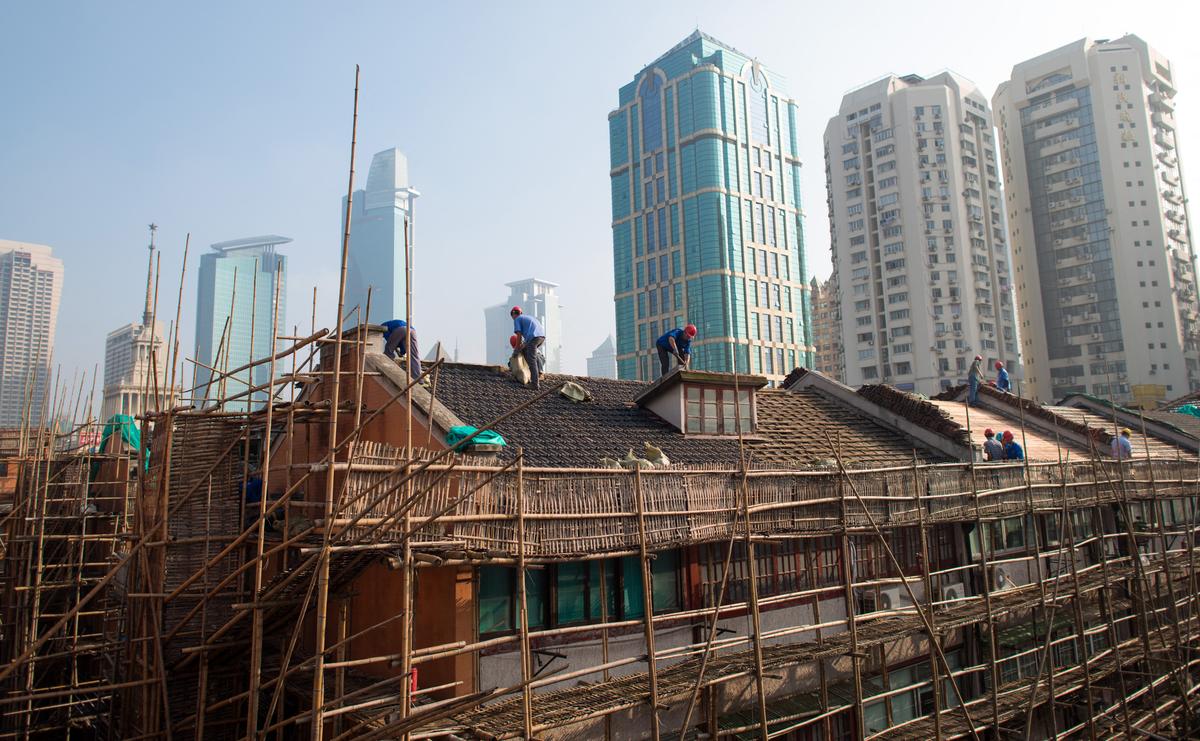 Labourers renovate a roof of a residential lane house in Shanghai on Aug. 21, 2014. (Johannes Eisele/AFP via Getty Images)