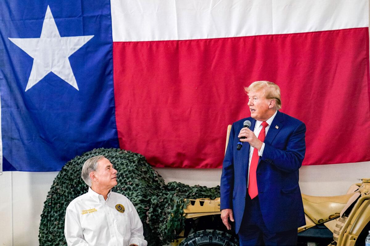 Texas Gov. Greg Abbott, left, listens as Republican presidential candidate and former President Donald Trump, right, speaks to Texas state troopers and guardsmen during a Thanksgiving meal at the South Texas International Airport, on Sunday, Nov. 19, 2023. (AP Photo/Eric Gay)