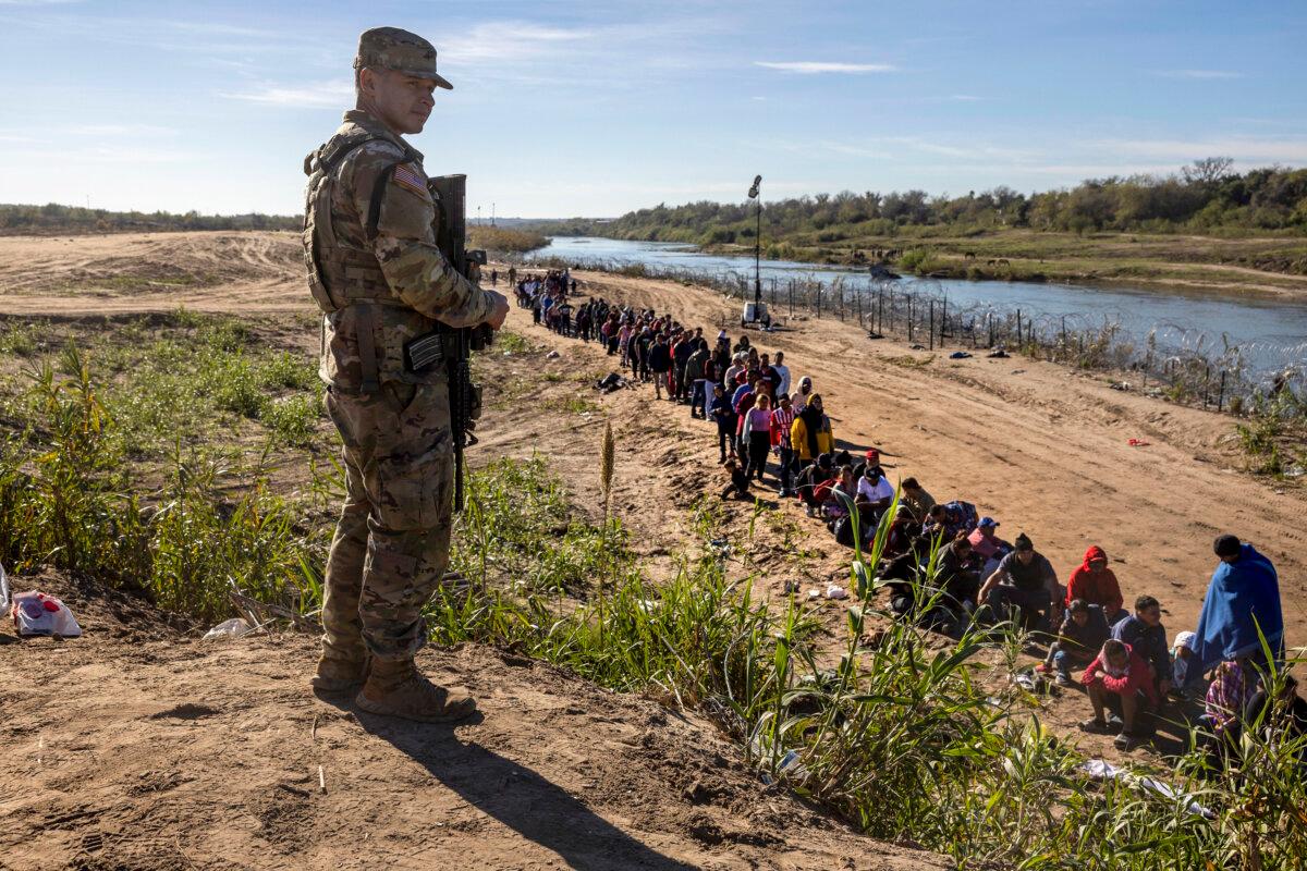 A Texas National Guard soldier watches over a group of more than 1,000 migrants who had crossed the Rio Grande from Mexico in Eagle Pass, Texas on Dec. 18, 2023. (John Moore/Getty Images)