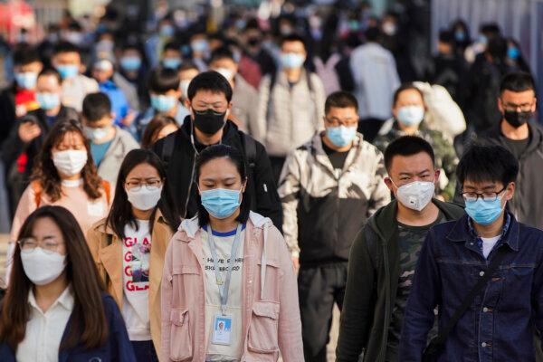 Commuters wear protective masks as they exit a subway station during rush hour on April 13, 2020, in Beijing, China. According to World Health Organization statistics, as of today, the number of confirmed cases of COVID-19 has exceeded 1.69 million, including 106,138 deaths. (Lintao Zhang/Getty Images)