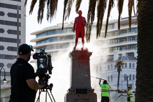 Members of the media record the cleaning process of a statue of Captain Cook at St. Kilda Beach in Melbourne, Australia on Jan. 26, 2022. (Diego Fedele/Getty Images)