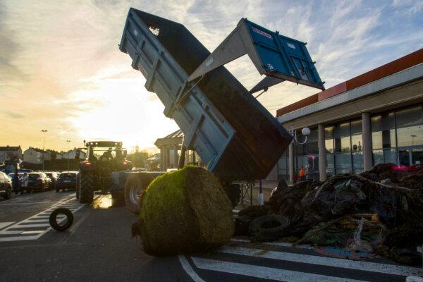 Farmers unload tyres and waste to block the entrance of a Leclerc supermarket in Le Mans, northwestern France, on Jan. 26, 2024, as part of a nationwide day of protests called by several farmers unions on pay, tax and regulations. Farmers have fumed at what they say is a squeeze on purchase prices for produce by supermarket and industrial buyers, as well as complex environmental regulations. (GUILLAUME SOUVANT/AFP)